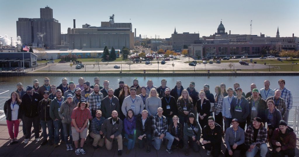 Group photo with the Briess malting facility in the background